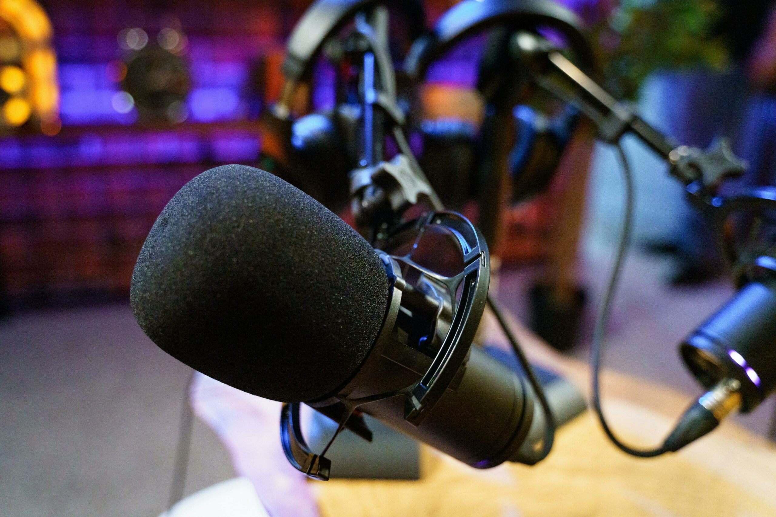 Close-up of a professional microphone in a studio setting with ambient purple lighting.